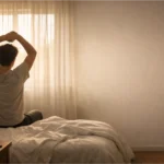 Person stretching in a bedroom with morning sunlight coming through the window