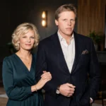 Portrait-style image of Judy Helkenberg standing with a man in elegant clothing in a stylish indoor setting.